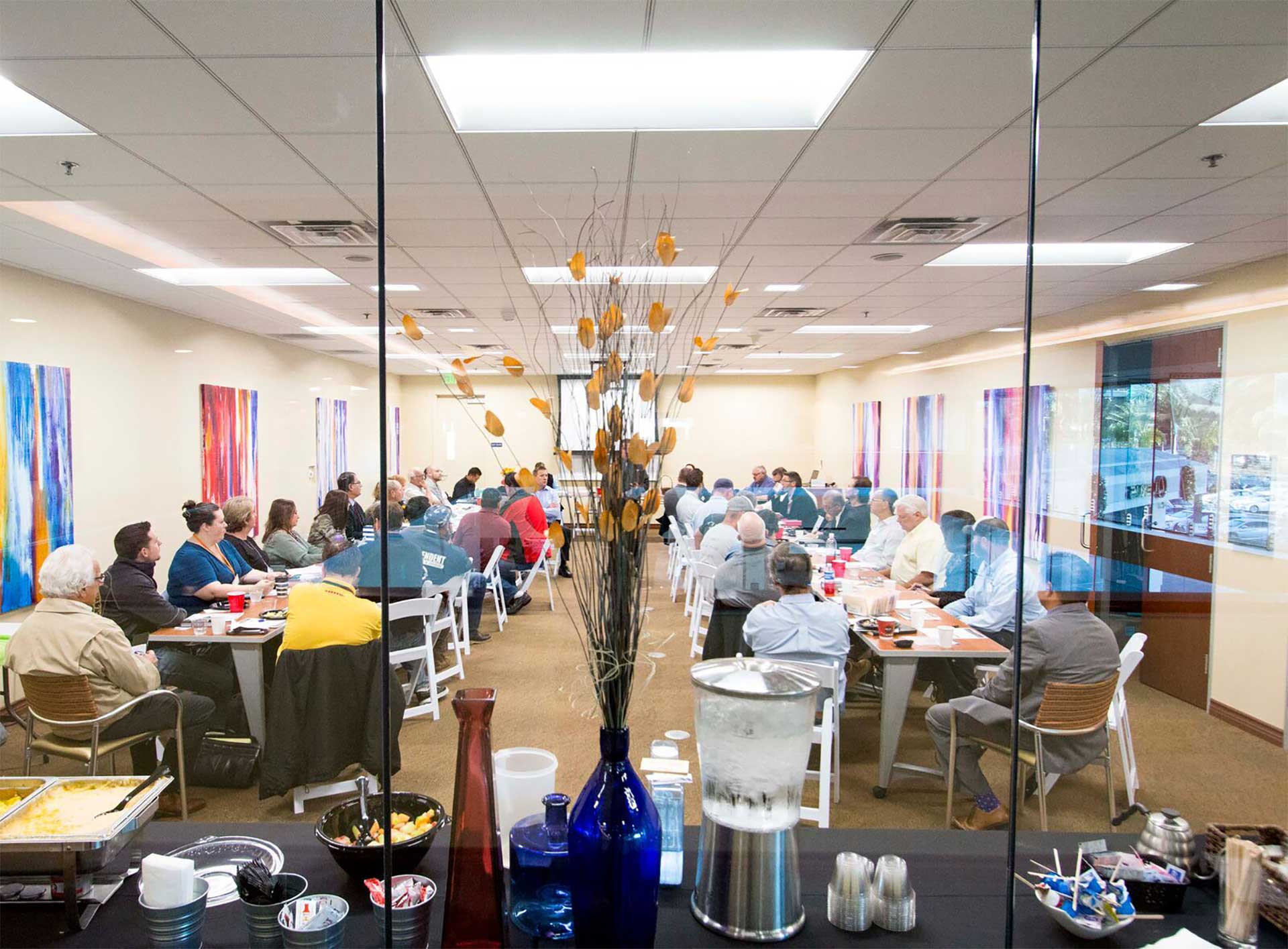 a corporate training being hosted in a meeting space in Escondido California. It is filled with attendees and a speaker at front.