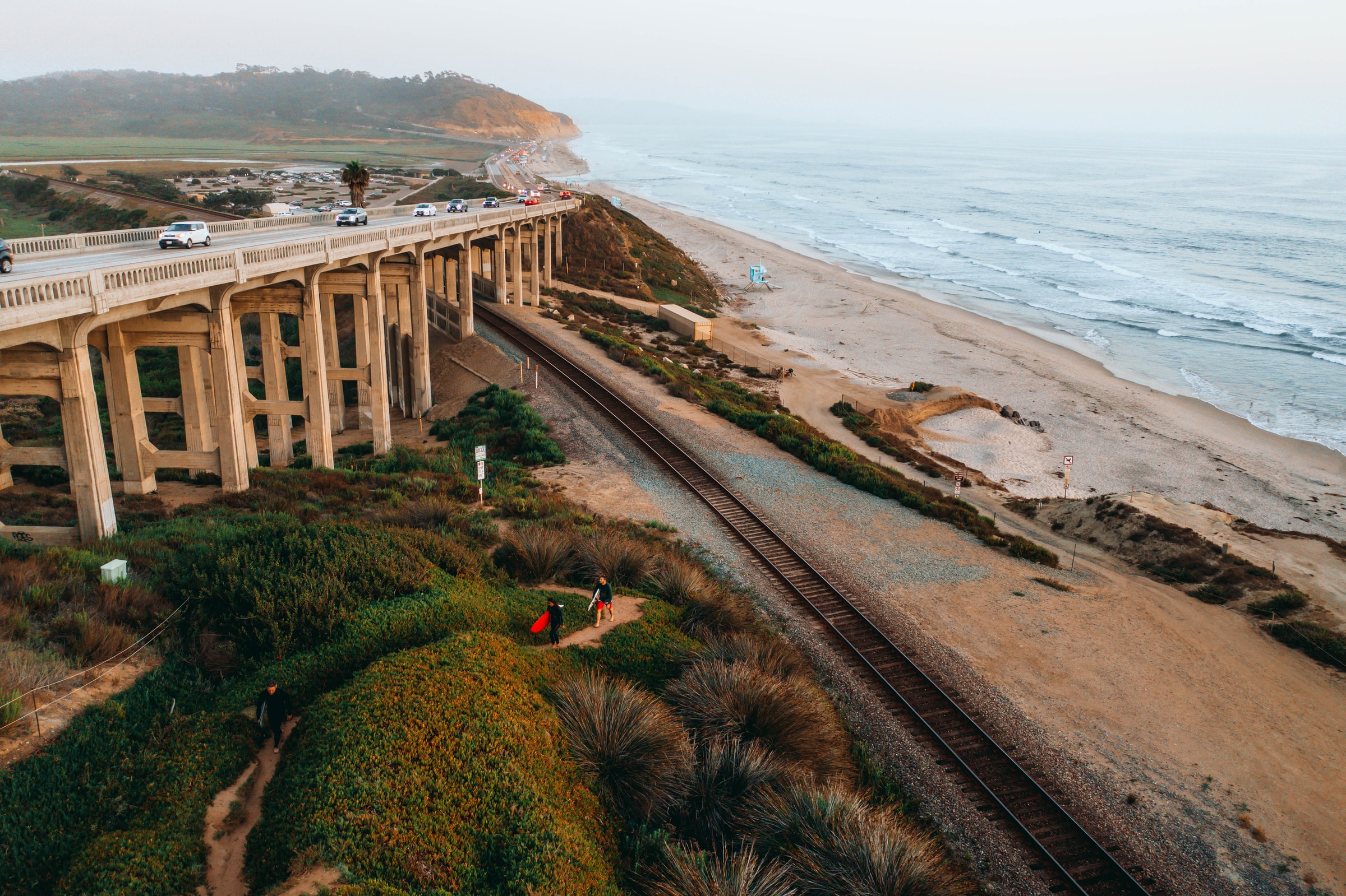 A photo of the Torrey Pines beach in San Diego County, one of the most beautiful spots for a destination wedding. The photo shows the road, coast, and cliffs agains the moving sea.