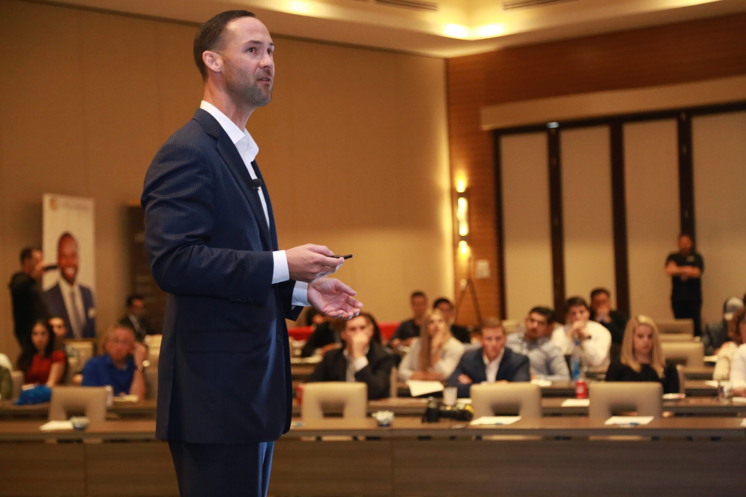 A man in front of a room full of people giving a shareholder meeting presentation
