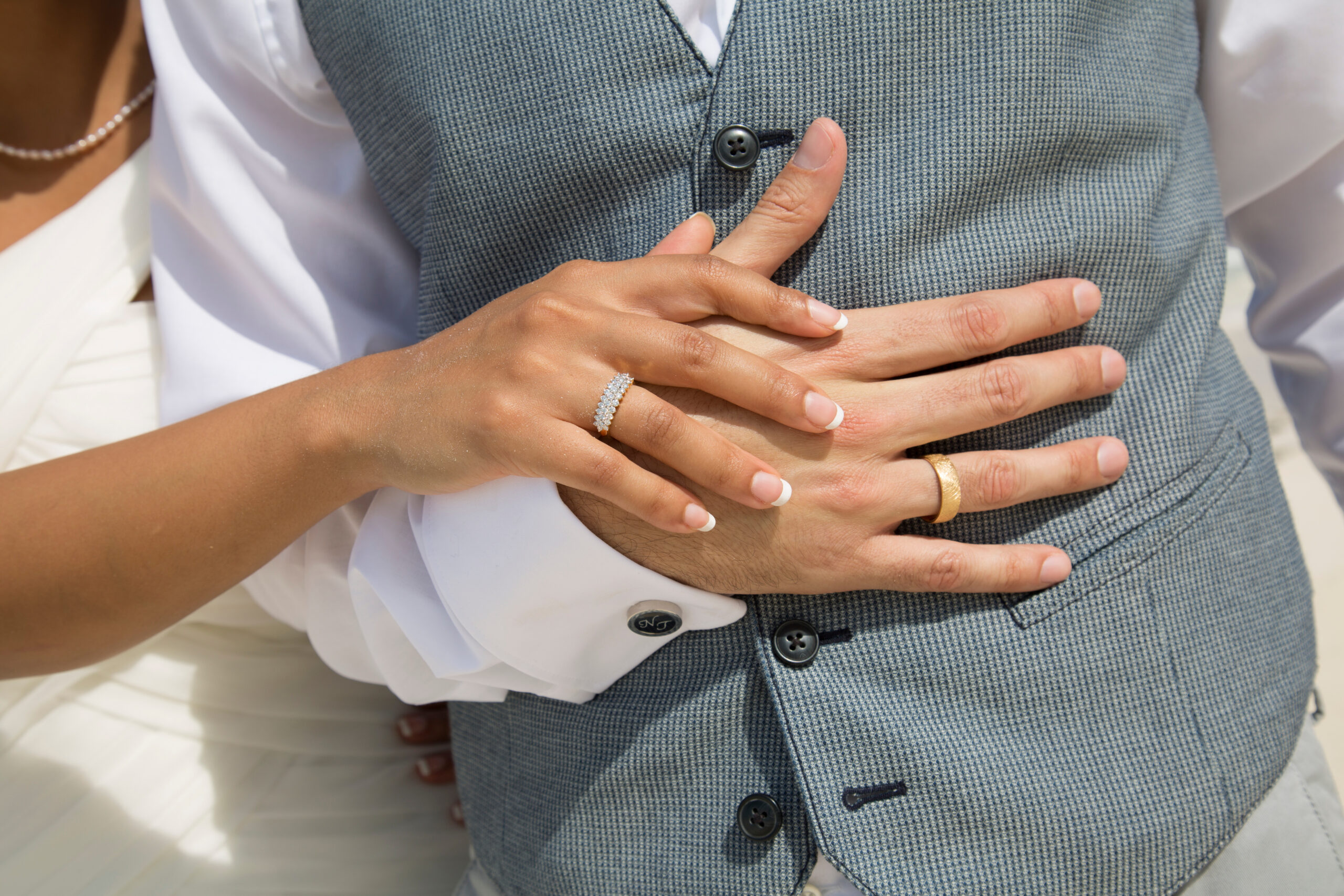 Close up of a wife's hand over her husband's with their wedding bands on for a vow renewal.