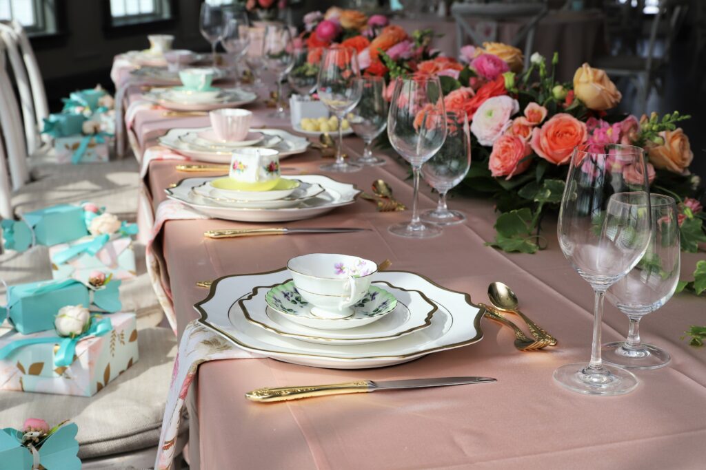 Table set up for bridal luncheon on bright summer day with flowers and vintage tea cups on each plate
