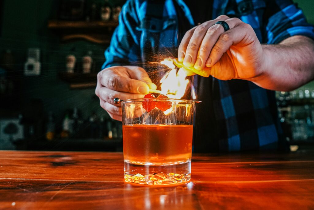 A mixologist lighting a cherry on top of bourbon for a mixology demonstration at a corporate event.